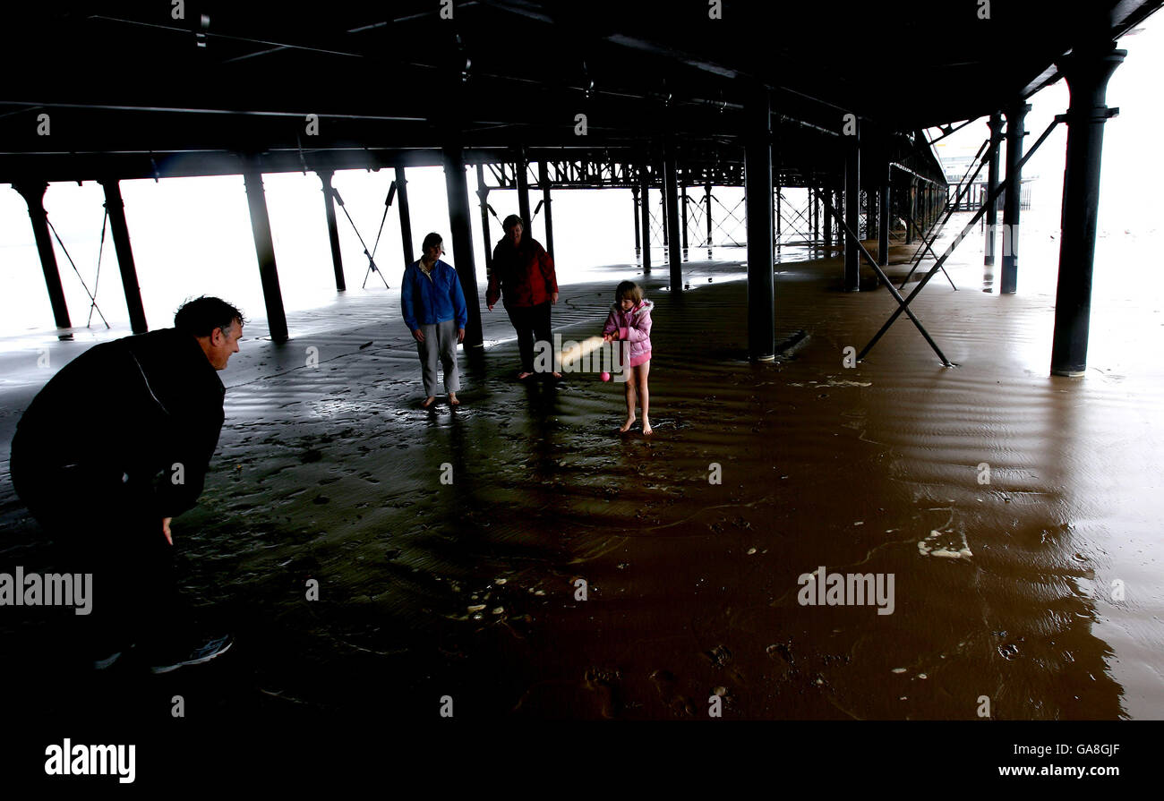 I vacanzieri fanno del meglio del maltempo giocando a cricket sotto la copertura del molo di Weston-Super-Mare nel Somerset. Foto Stock