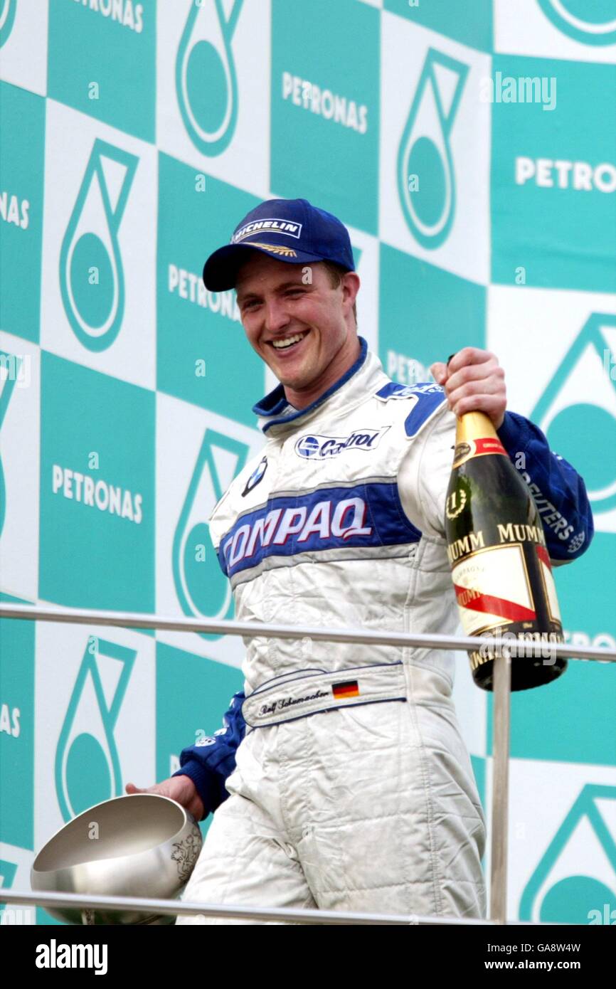 Formula uno Motor Racing - Gran Premio della Malesia - gara. La BMW Williams di Ralf Schumacher sorride e cammina fuori dal podio bevendo champagne dopo aver vinto la gara Foto Stock