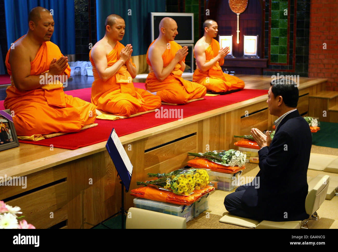 Il Dr. Thaksin Shinawatra, ex primo Ministro della Thailandia, prega con i monaci al Dhammakaya Center for Buddiste Meditation a Knaphill, Surrey, un anno dopo essere stato cacciato dall'ufficio. Foto Stock