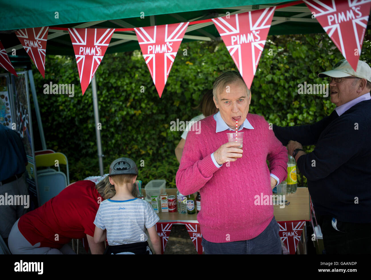 Un uomo che beve un Pimm's Cup cocktail durante un villaggio Fete in Worth Matravers Dorset, Regno Unito Foto Stock