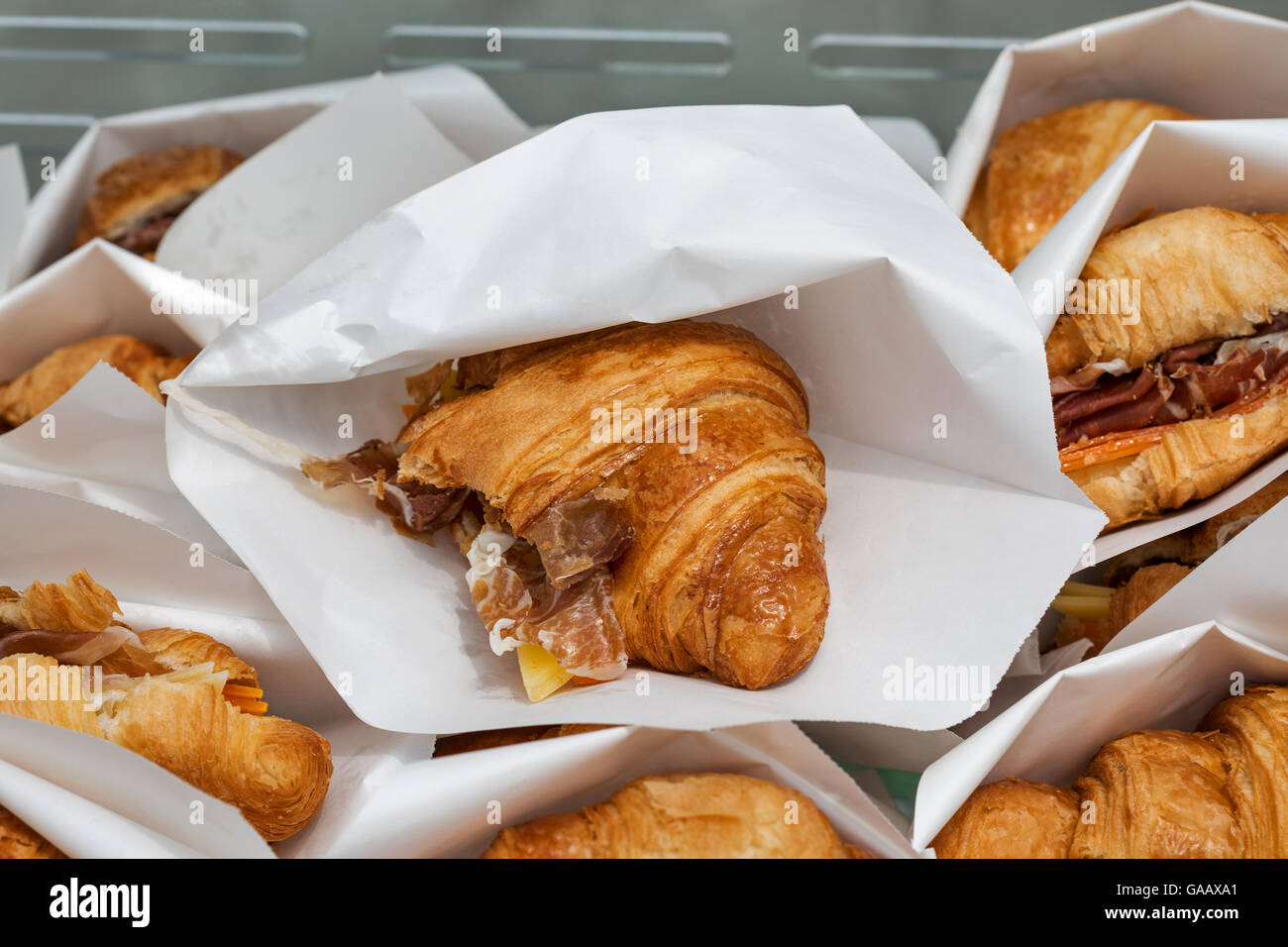 Cucina di strada croissant con prosciutto e formaggio servita in sacchi di carta closeup Foto Stock