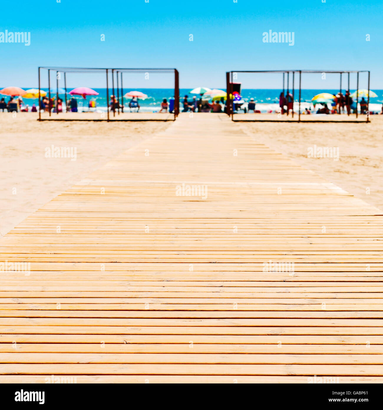 Passerella in legno a San Antonio Il Spiaggia di Cullera, Spagna, con il mare Mediterraneo e irriconoscibile lucertole da mare in bac Foto Stock