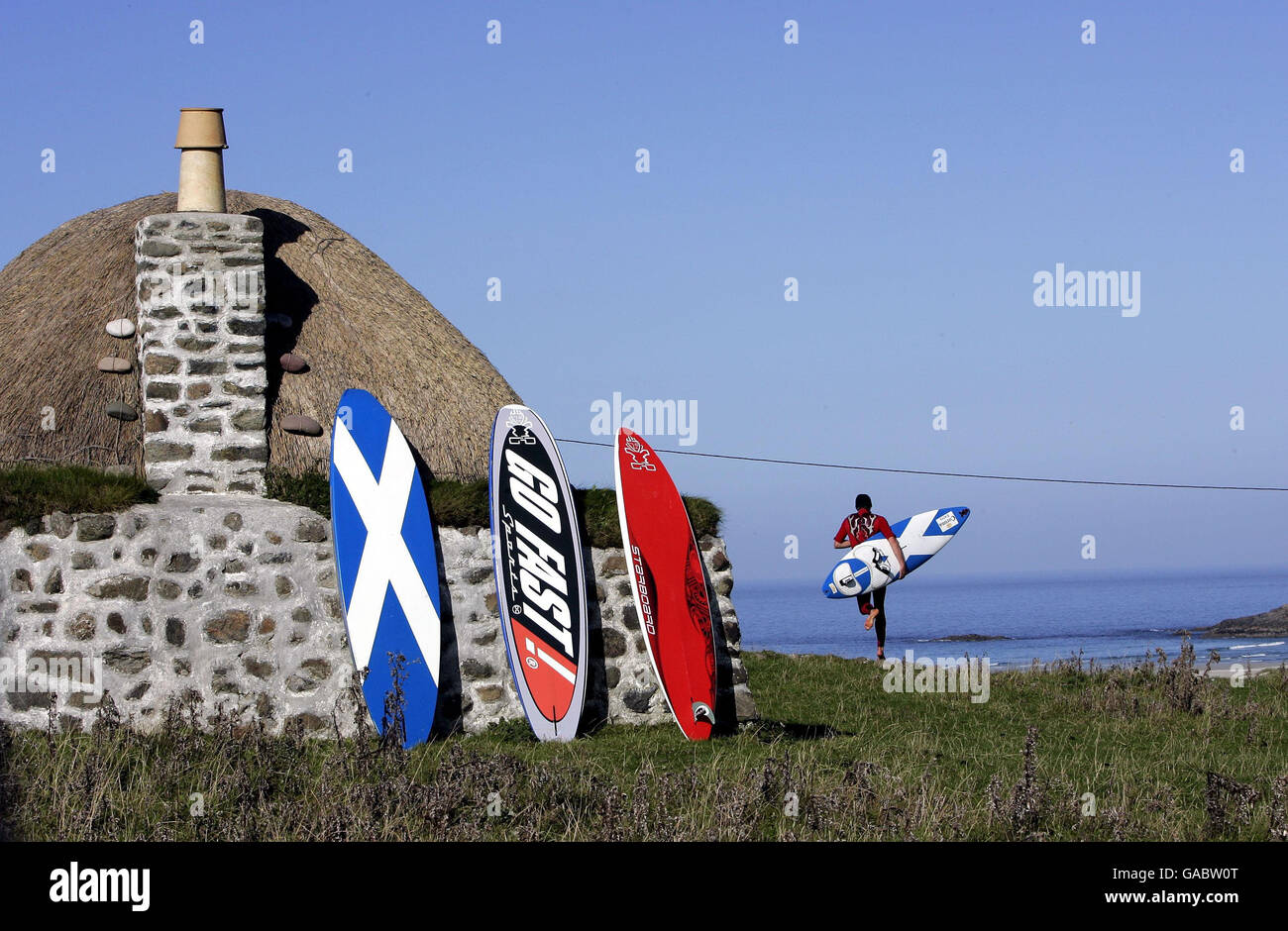 Il concorrente britannico John Hibard corre verso la spiaggia di Balevullin sull'isola di Tiree in un giorno il tempo era troppo calmo per il surf, ma perfetto per prendere il sole, durante la Corona Extra PWA (Professional Windsurf Association) World Cup che si tiene sull'isola. Foto Stock