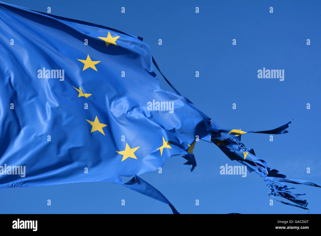 L'Unione europea dodici stelle bandiera strappata e con nodi di vento sul cielo blu Foto Stock