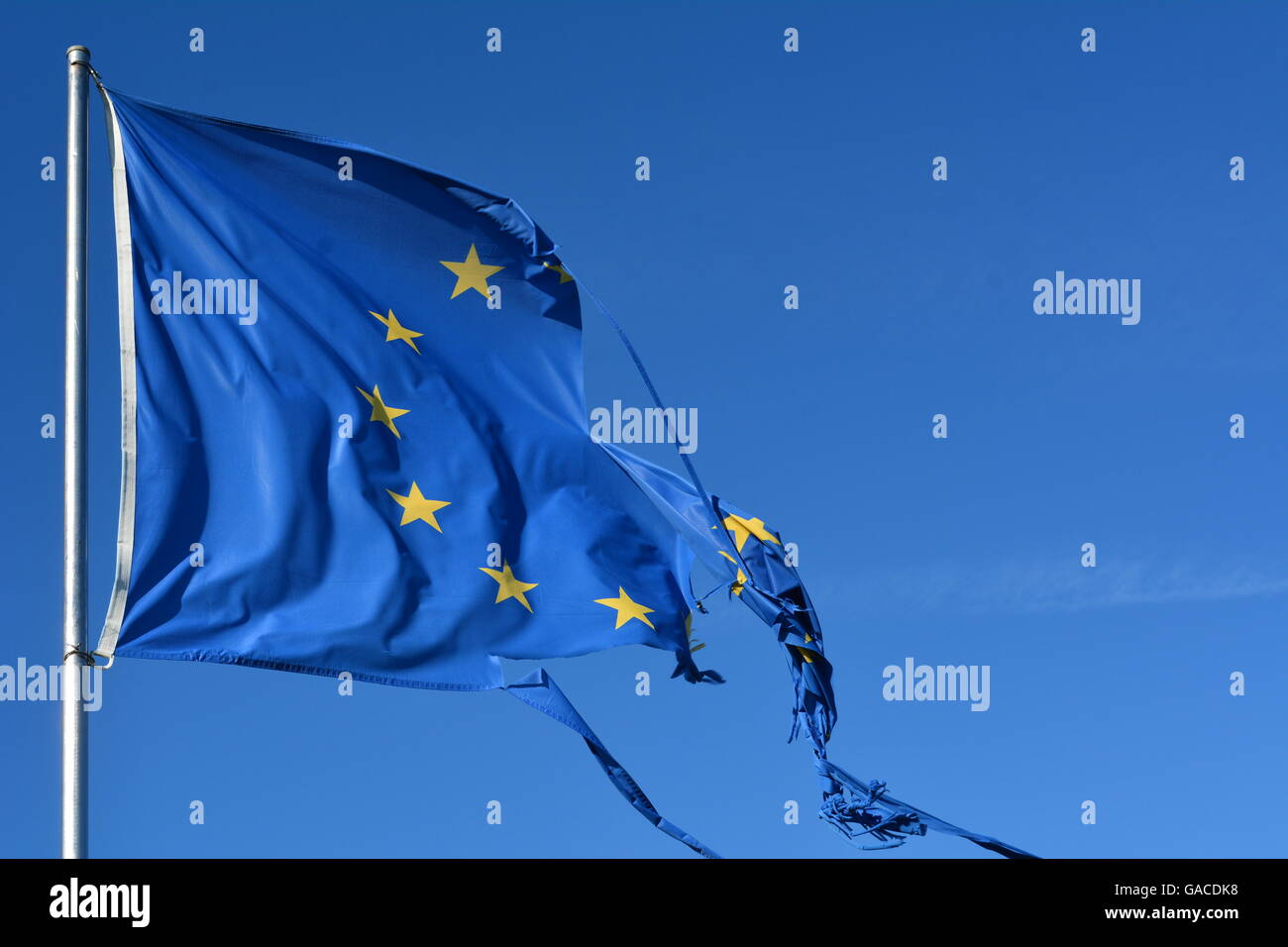 L'Unione europea dodici stelle bandiera strappata e con nodi di vento sul cielo blu Foto Stock