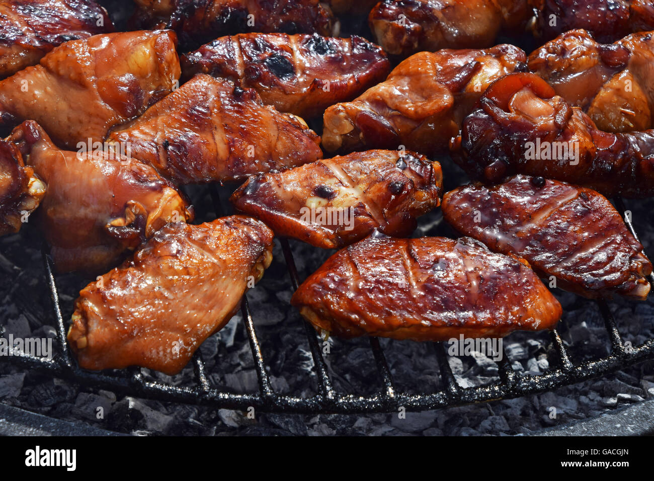 Bufali di pollo o salsa teriyaki ali cotta alla brace sul fumo barbecue grill rotondo, close up Foto Stock