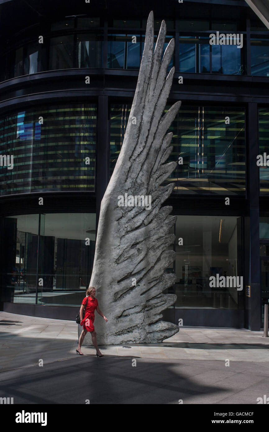 I lavoratori della città passa dal gigante illustrazione di una ala di bronzo durante un pranzo di primavera nel quartiere finanziario di Londra, il 4 luglio, Londra, Regno Unito. Come la luce si riflette nei dintorni di edifici per uffici, la folla durante la pausa pranzo a piedi passato questo gigante artwork sul loro modo di riunioni e barre di sandwich. La decina di metri di altezza scultura in bronzo è dal presidente della Royal Academy of Arts, Christopher Le Brun, commissionato da Hammerson nel 2009. Esso è chiamato 'l'ala della città " ed è stato gettato da Morris cantante arte Fondatori, ripetutamente la più antica arte fonderia in tutto il mondo. Foto Stock