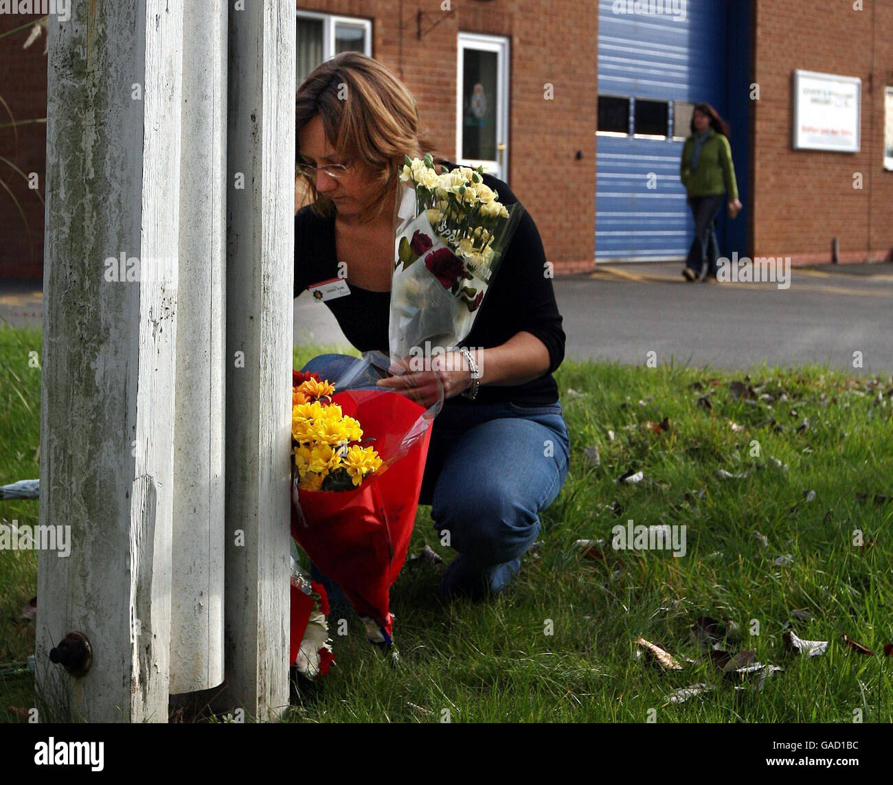 Un addetto ai vigili del fuoco organizza i fiori alla base del flagpole presso la stazione dei vigili del fuoco di Stratford-upon-Avon. Quattro vigili del fuoco sono ritenuti uccisi in un deposito notturno Blaze nella vicina Atherstone su Stour. Foto Stock