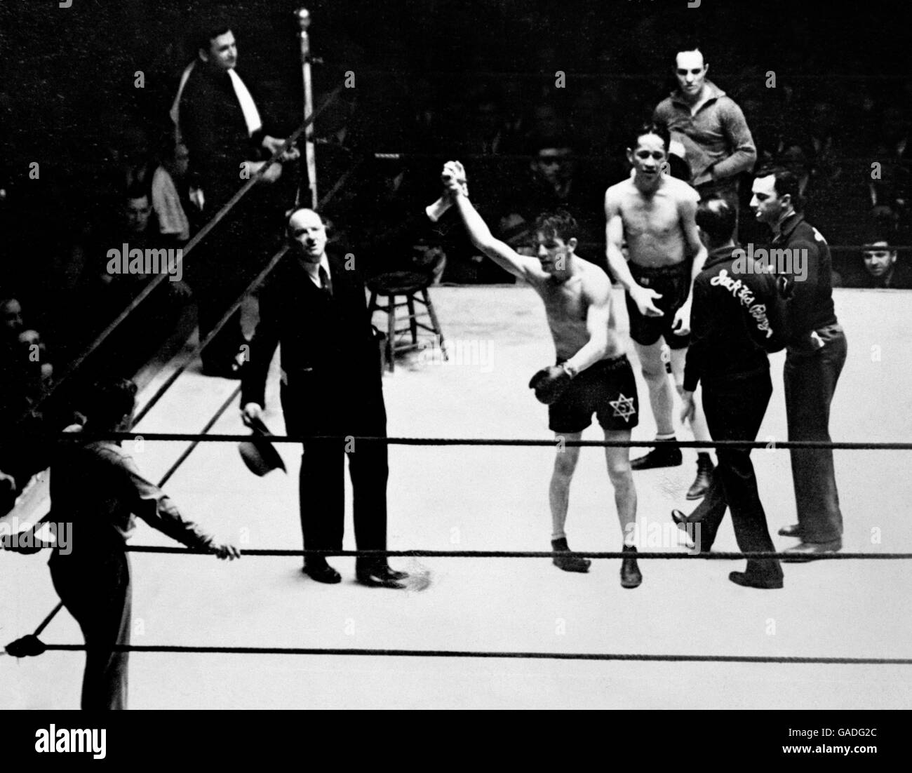 L'annunciatore Joe Humphries alza la mano del vincitore, il pugile britannico Jack 'Kid' Berg, aka 'il whirlwind Whitechapel' che ha battuto il pugile americano Tony Herrera, aka, 'la sinfonia in pelle'. La lotta si è svolta a Madison Square Gardens nel maggio 1931. Foto Stock