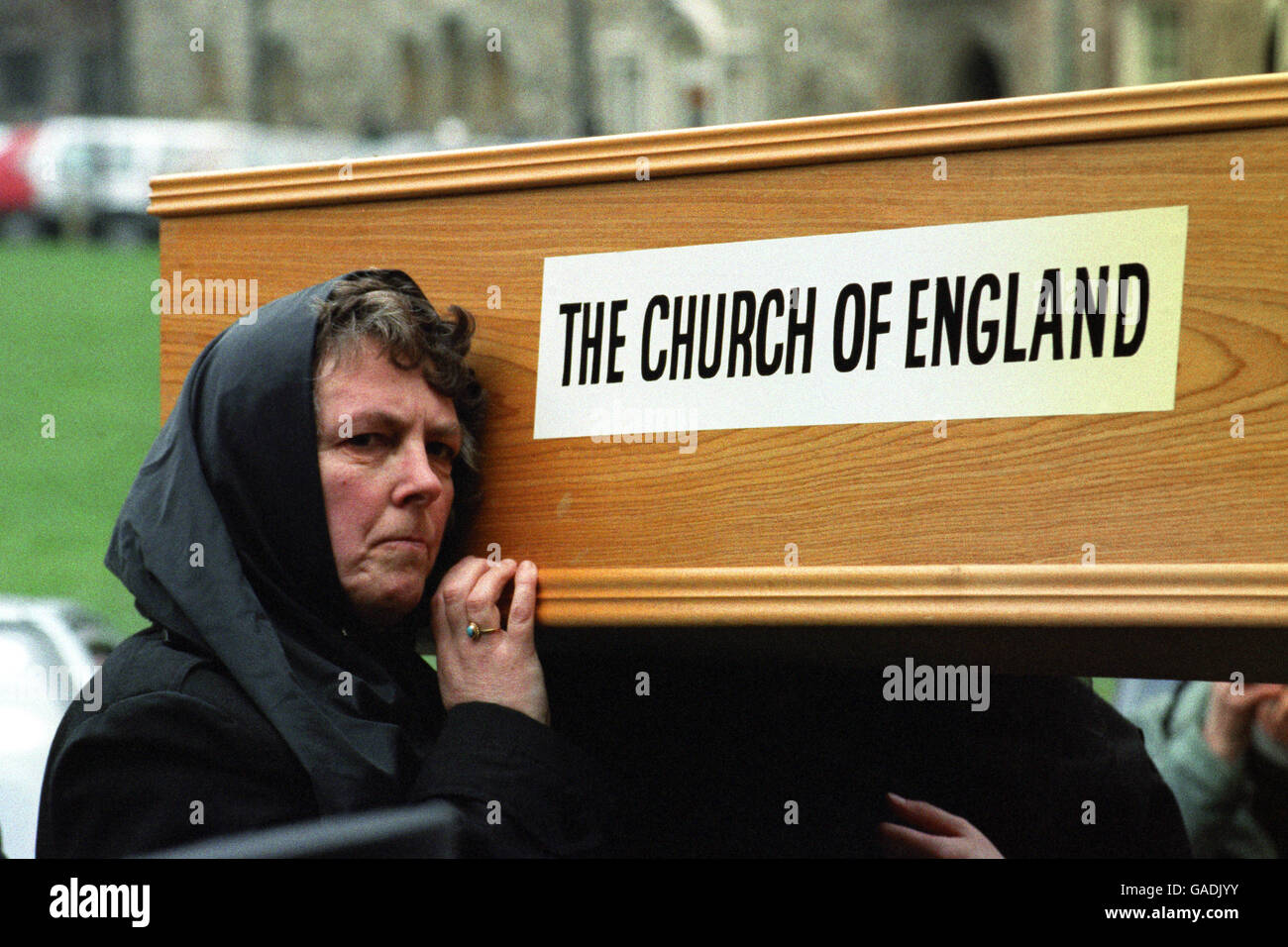 Una donna aiuta a portare una bara a simboleggiare gli ultimi riti della Chiesa d'Inghilterra. L'Ecclesia guidata da Padre Francis Bown, ha organizzato la protesta il giorno dell'incontro sinodale generale a Westminster. Foto Stock