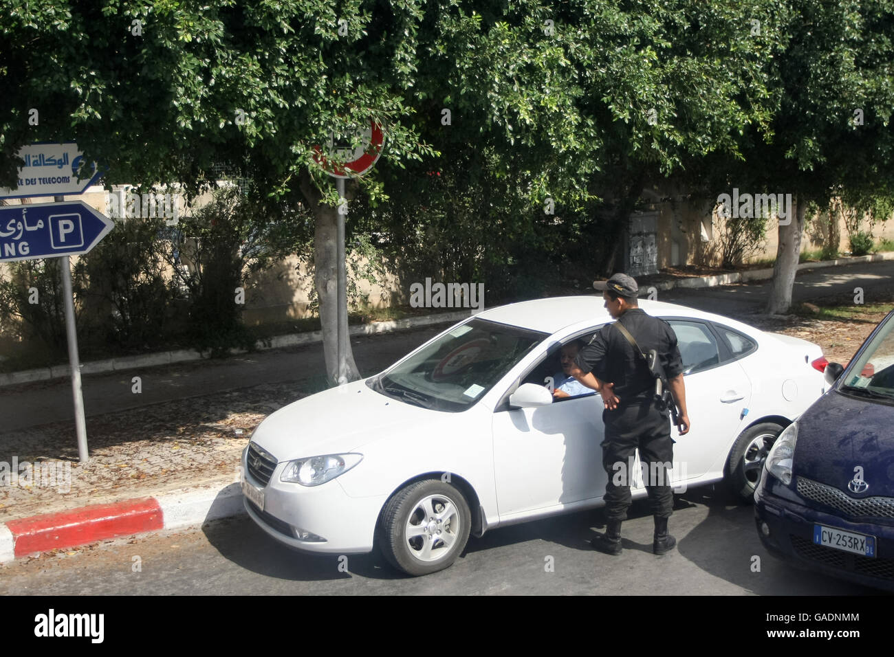 Un poliziotto la verifica di un driver nella macchina parcheggiata sul lato della strada dal porto di Port El Kantaoui, a Sousse, Tunisia. Foto Stock