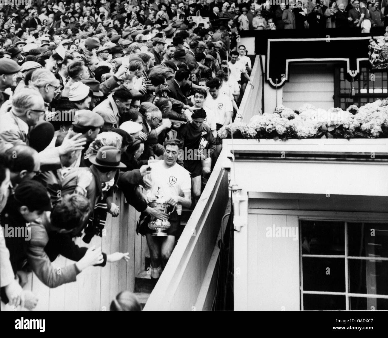 Il capitano Tottenham Hotspur Danny Blanchflower tiene saldamente la fa Cup mentre lui e i suoi compagni di squadra, quasi sepolti sotto le congratulazioni della folla, fanno il loro senso indietro giù i gradini dalla scatola reale: (Dal basso verso l'alto) Blanchflower, Bill Brown, Ron Henry, Maurice Norman, Peter Baker, Les Allen (nascosto), John White, Cliff Jones, Terry Dyson, Bobby Smith, Dave Mackay Foto Stock