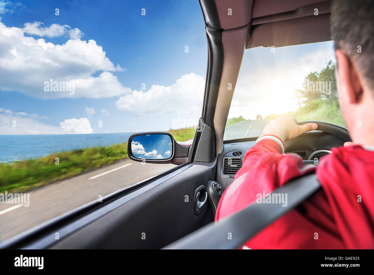 Driver maschio aziona una autovettura convertibile sulla strada del paese dal mare. La vista dalla cabina, vista posteriore, all'interno. Foto Stock