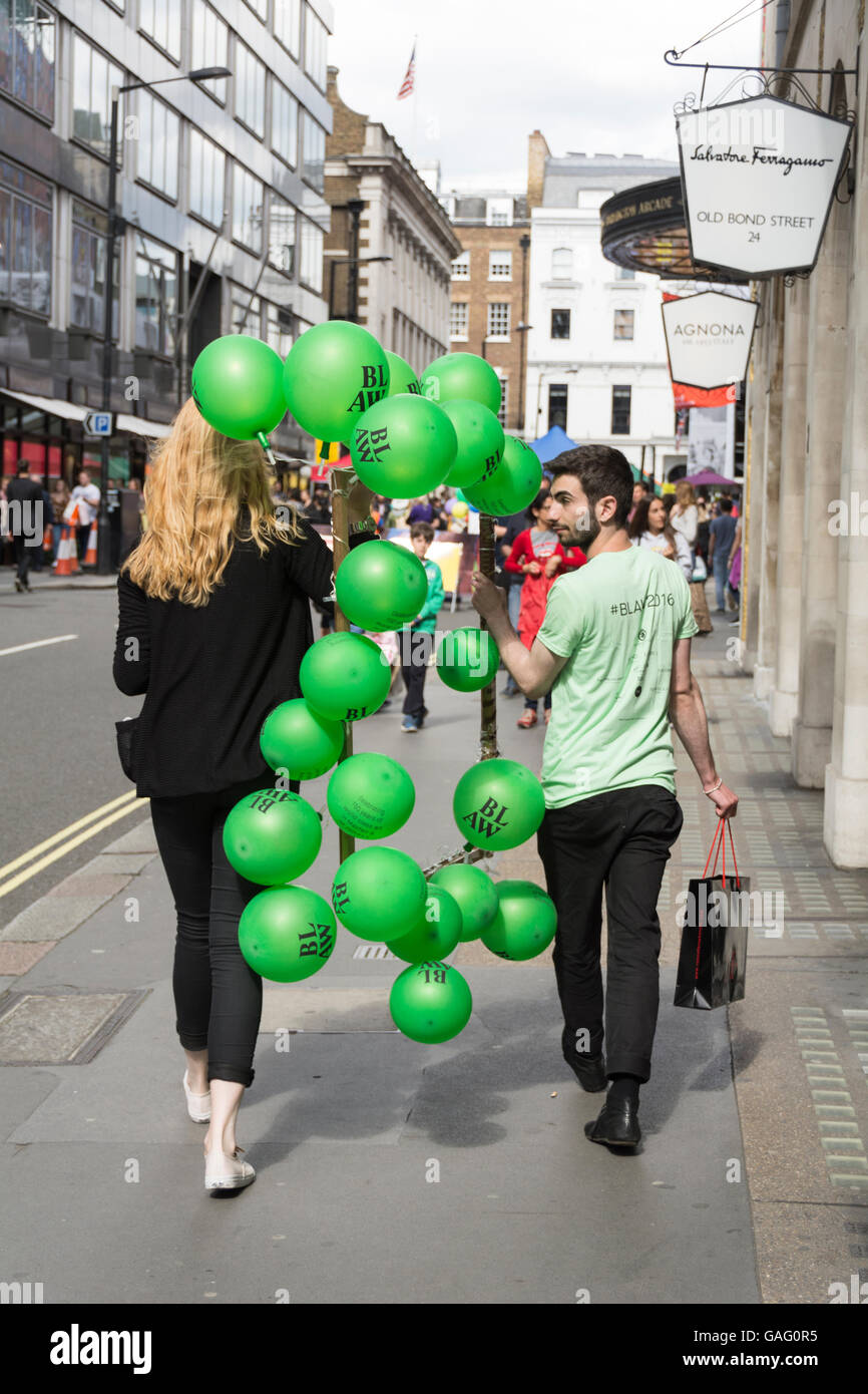 Un uomo e una donna con palloncini verde in Burlington Gardens, London, W1 Foto Stock Un uomo e una donna con palloncini verde in Burlington Gardens, London, W1 Foto Stock