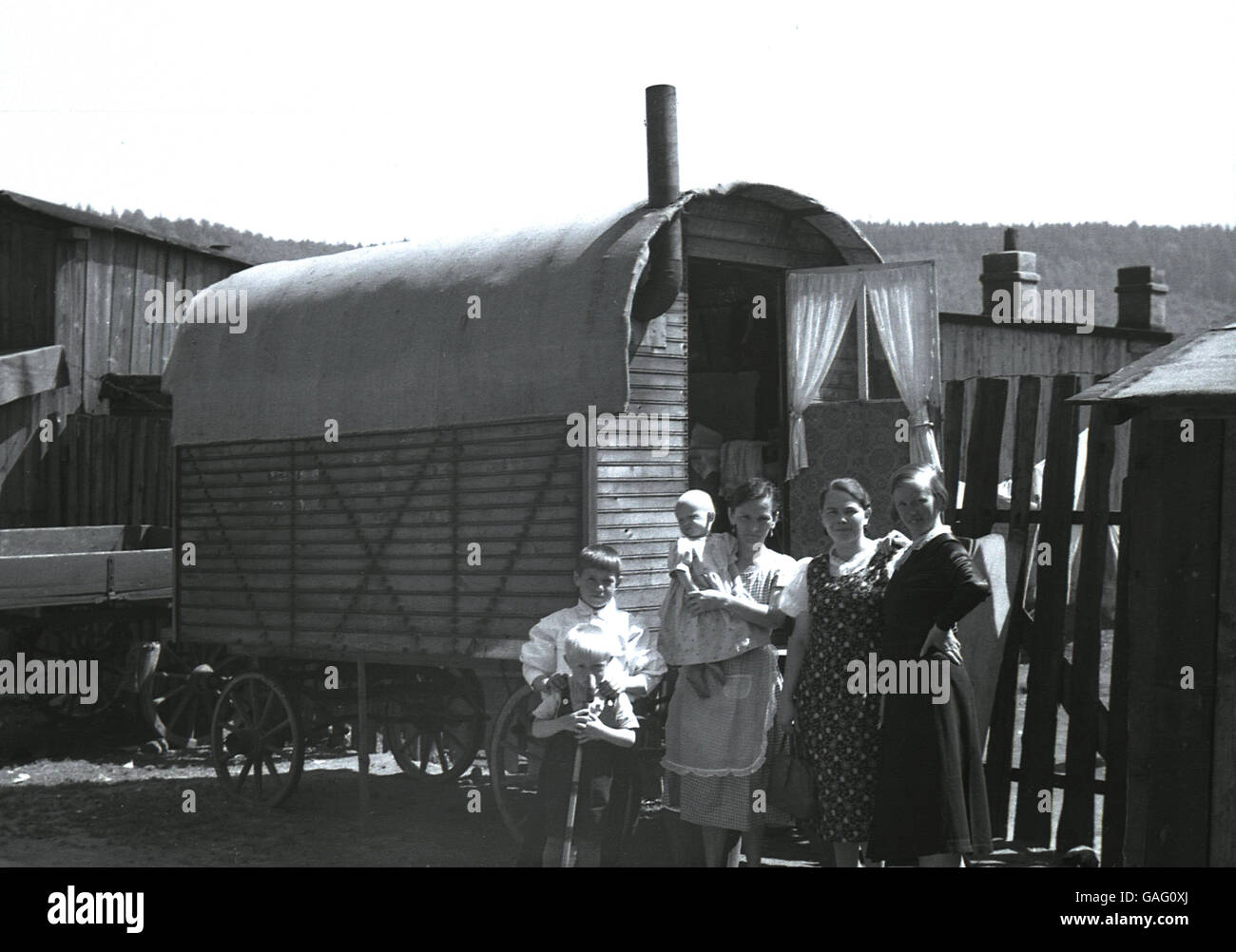 1930s, storico madre con bambino e i figli piccoli stand al di fuori della loro casa. un caravan di legno su ruote, su un maso vicino Elbogen, Sudentenland, in pre-ww11 Cecoslovacchia. Foto Stock