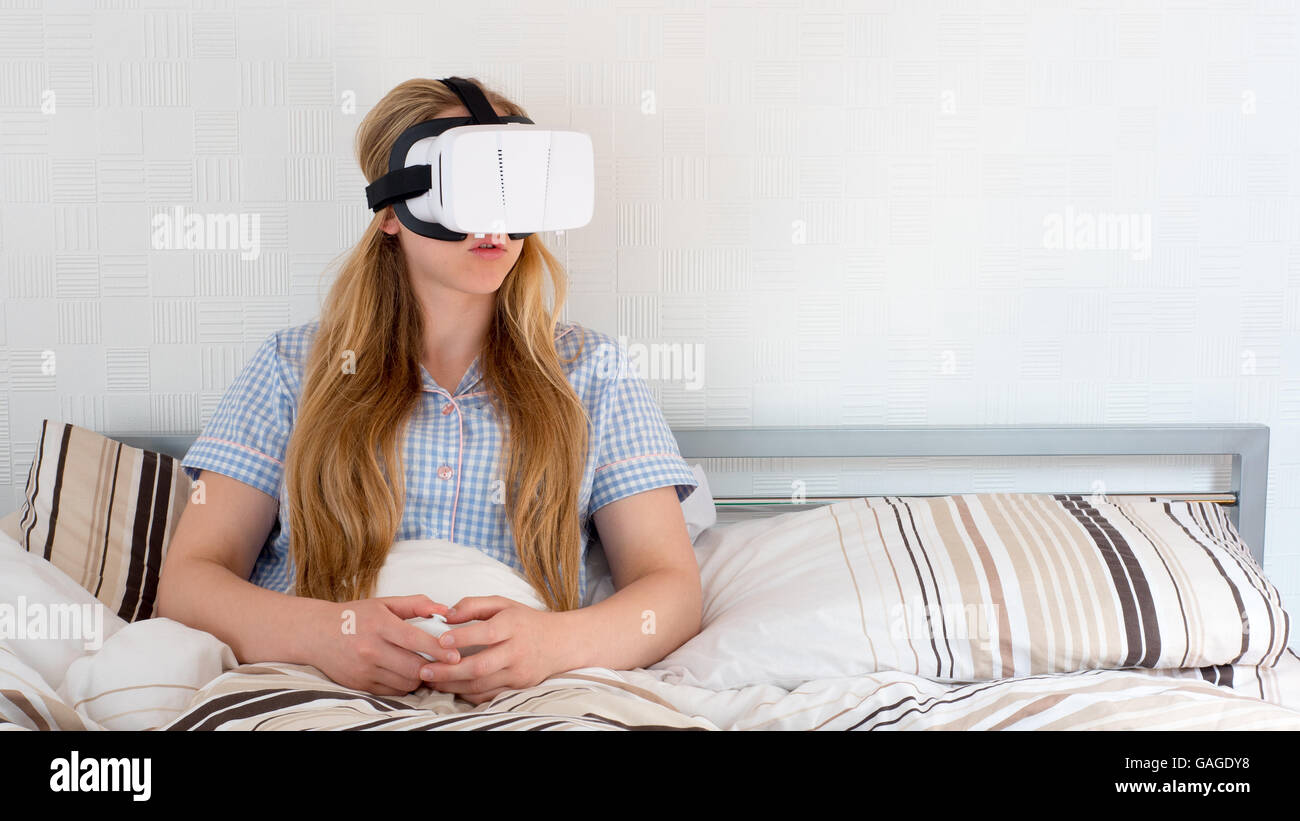 Bella donna utilizzando cuffie VR a letto Foto Stock
