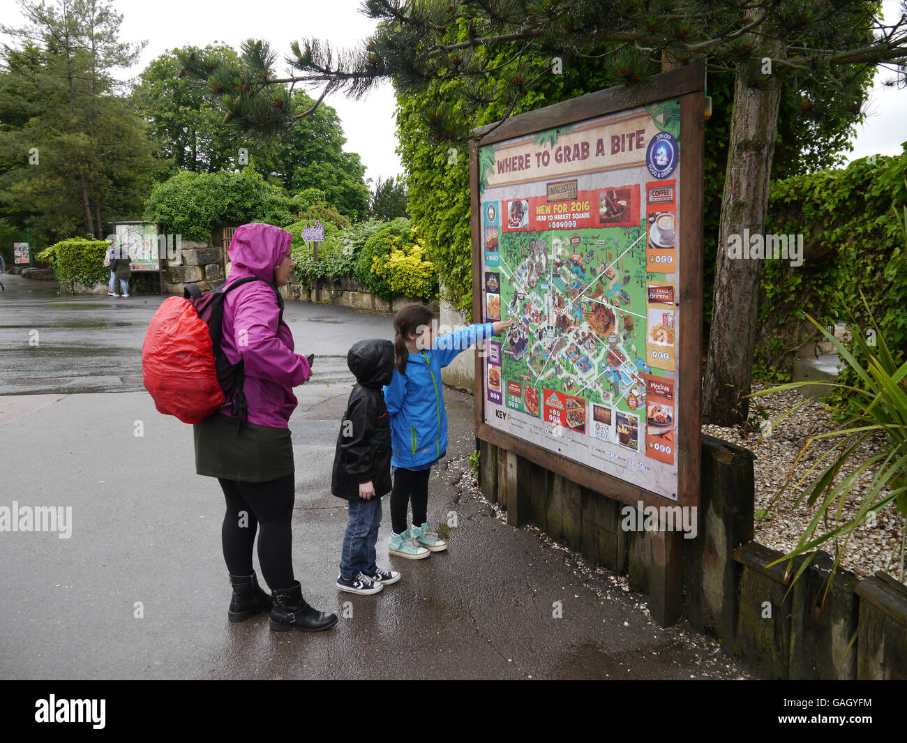 Una madre e due bambini guarda la mappa di un parco a tema Foto Stock