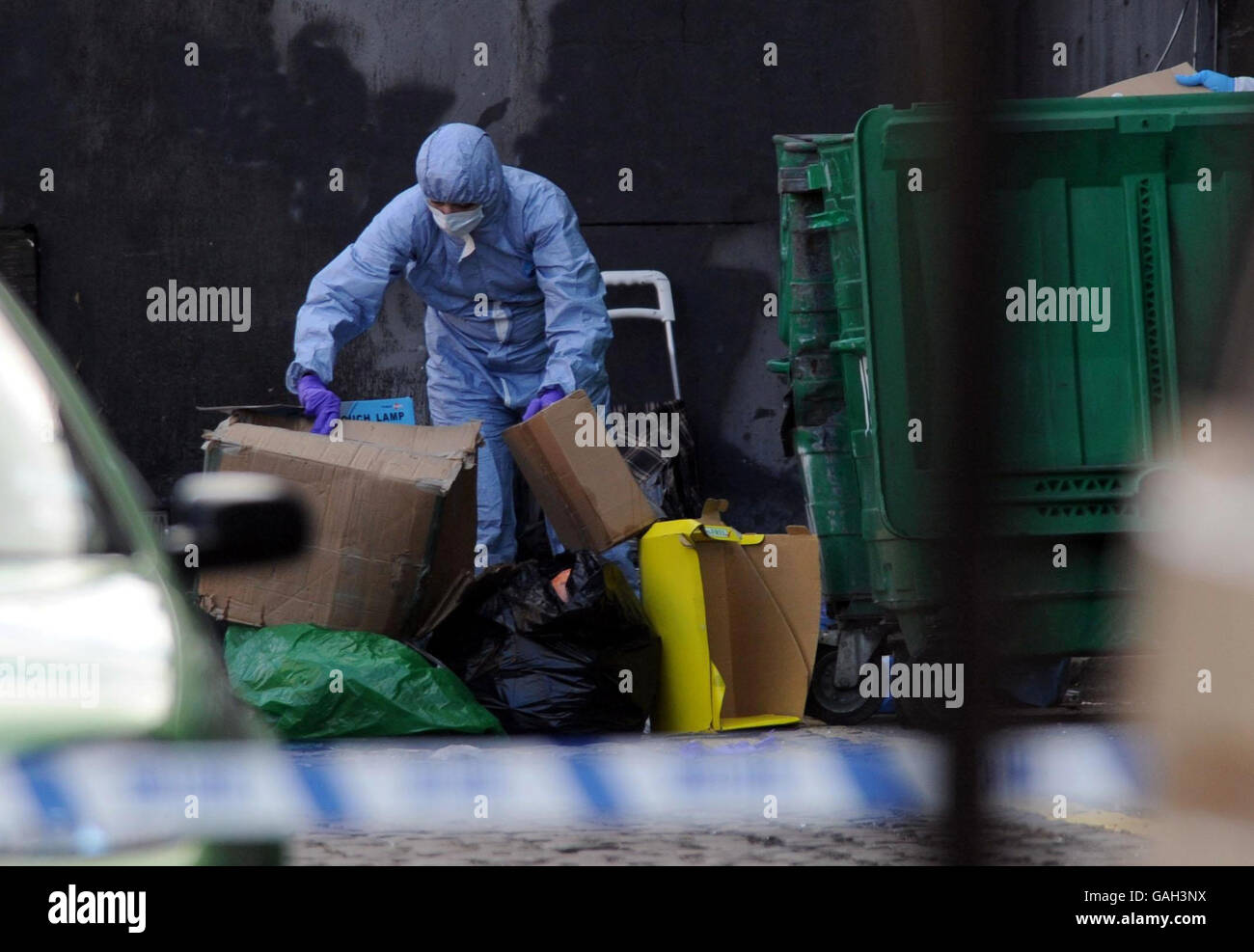 Un ufficiale di polizia forense assiste la scena a Kilburn, a nord di Londra, dopo la scoperta di un corpo avvolto in fogli. Foto Stock