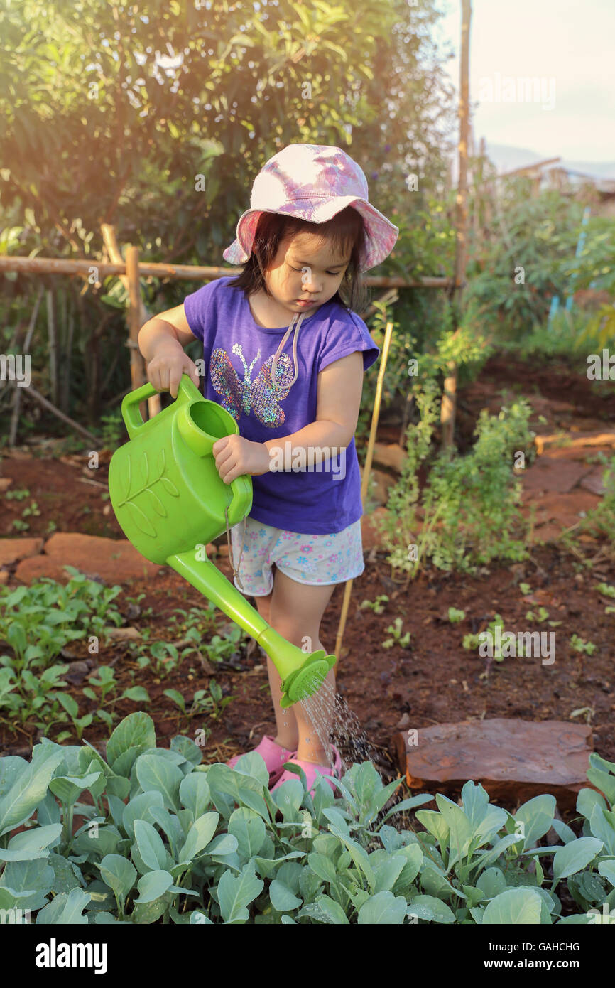 Bambina con annaffiatoio piante acquatiche in giardino, montessori concetto di istruzione Foto Stock