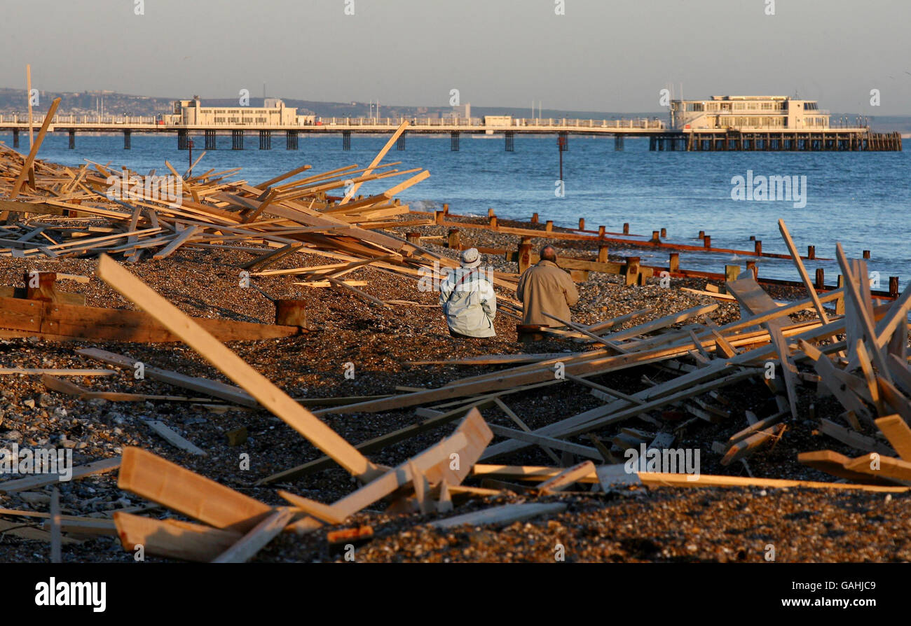 Una coppia sulla spiaggia a Worthing, West Sussex, mentre l'operazione di pulizia di legno lavato ashore dalla nave Ice Prince continua. Foto Stock