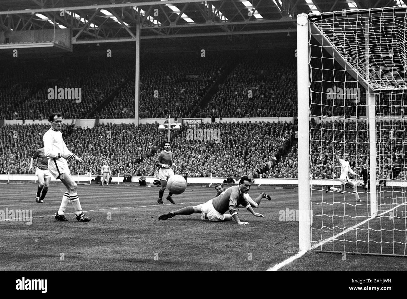 Calcio - fa Cup - finale - Manchester United / Leicester City. Il Manchester United's Noel Cantwell (c, sul pavimento) guarda la palla volare stretto largo del suo obiettivo dopo aver ottenuto un leggero tocco su una croce Foto Stock