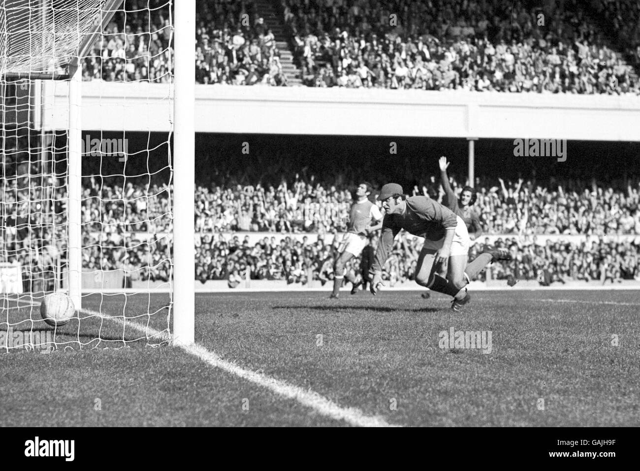 Il George Best (r, parzialmente nascosto) del Manchester United alza il braccio in celebrazione come il suo colpo batte il portiere dell'Arsenal Malcolm Webster per arricciarsi nell'angolo lontano della rete Foto Stock