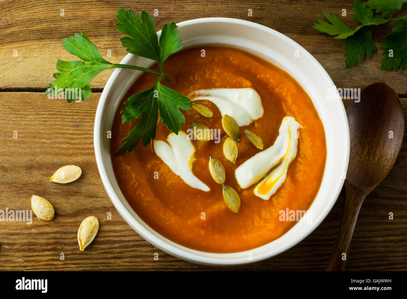 Arrosto zucca zucca minestra di crema con la panna e i semi di zucca in bianco la ciotola di legno scuro di sfondo, vista dall'alto Foto Stock