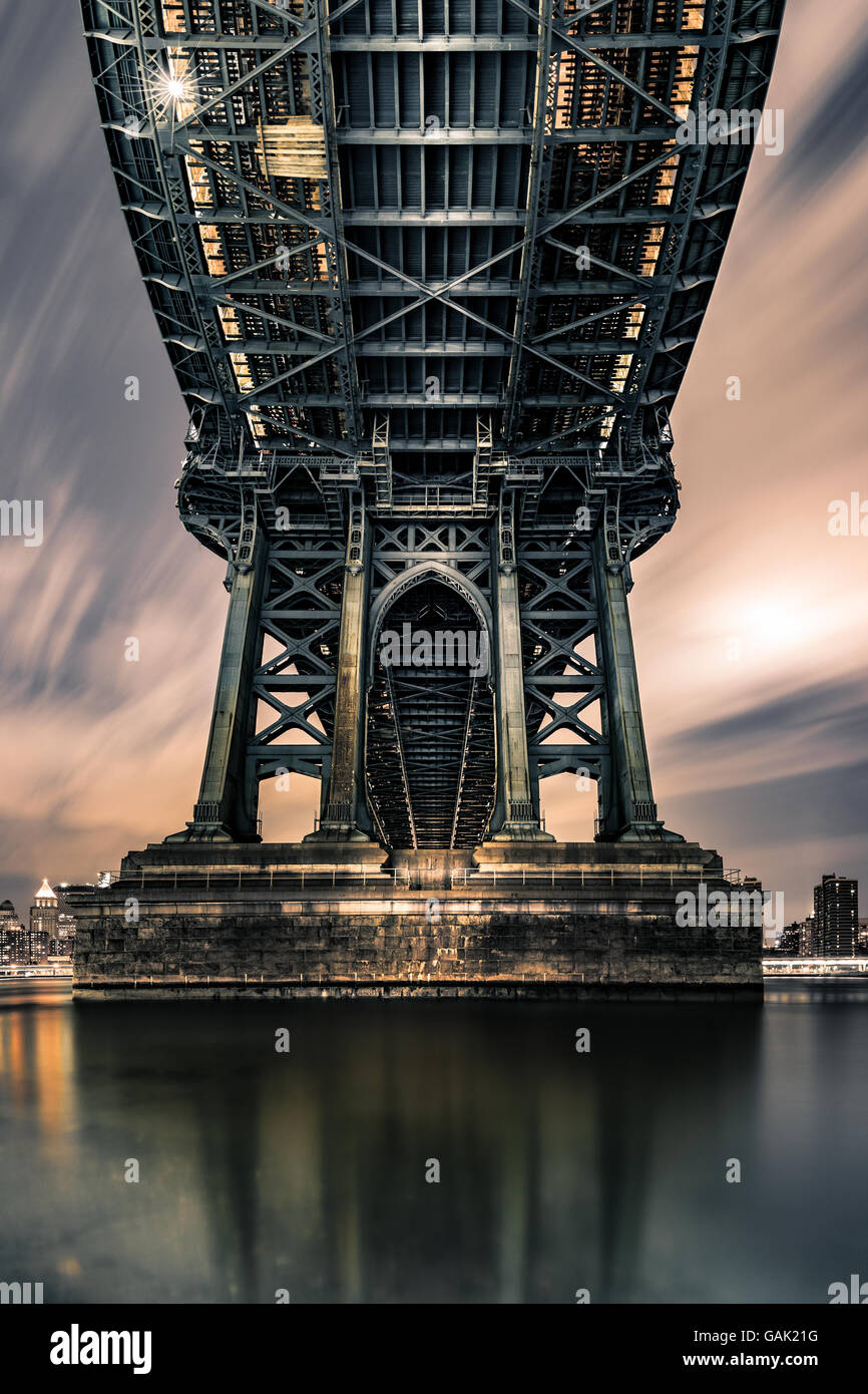 Moody prospettiva simmetrica sotto Manhattan Bridge di notte. Foto Stock