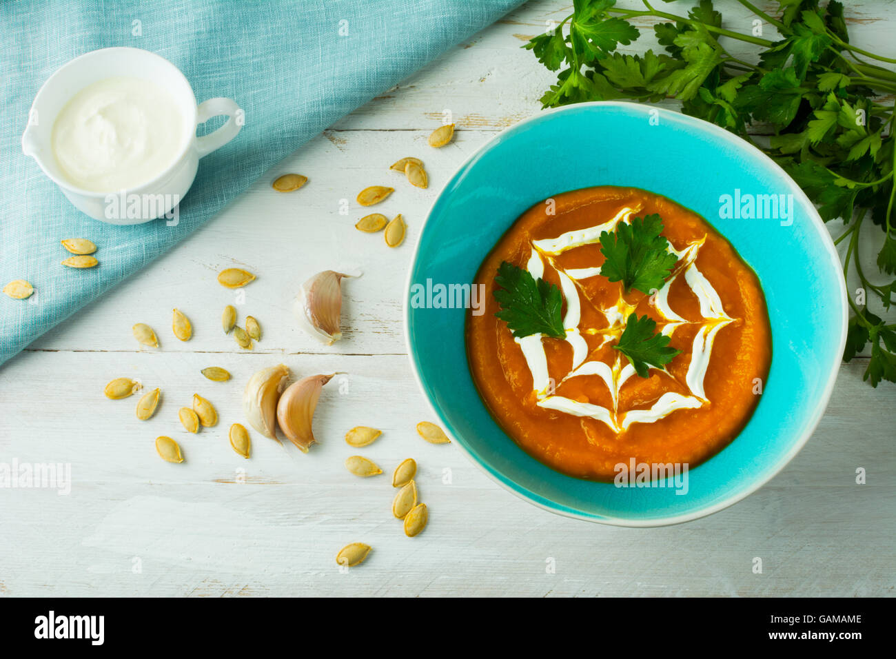 Crema di zucca zucca zuppa di verdura conditi con panna in una piastra di turchese, semi di zucca, aglio e prezzemolo, vista dall'alto Foto Stock