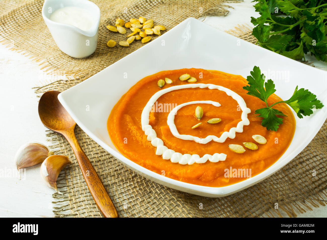 Arrosto zucca zucca minestra di verdura con crema, semi di zucca e prezzemolo in un quadrato bianco piastra su tela Foto Stock