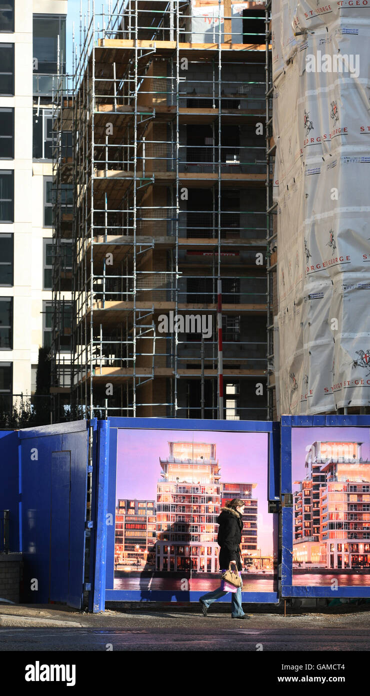 Un ciclista passa per un ingresso per veicoli da costruzione all'Imperial Wharf, un complesso misto di St George PLC (parte di Berkeley Group Holdings) sulle rive del Tamigi accanto al porto di Chelsea. Foto Stock