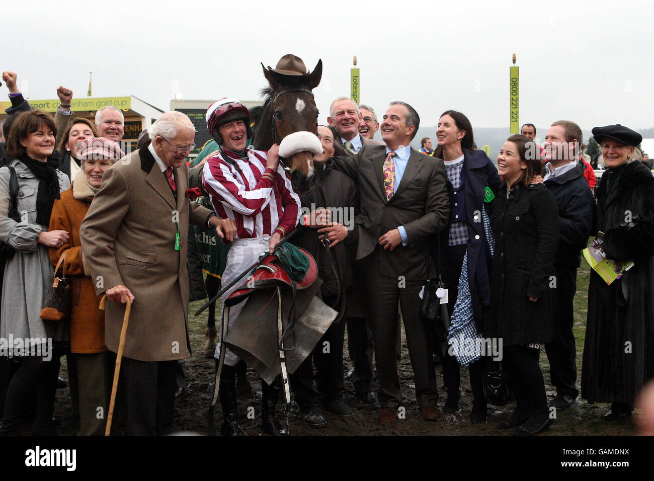 Tiger Cry con il fantino Davy Russell e il proprietario Chris Jones (con bastone) dopo aver vinto il Johnny Henderson Grand Annual Steeple Chase durante il Cheltenham Festival all'ippodromo di Cheltenham. Foto Stock
