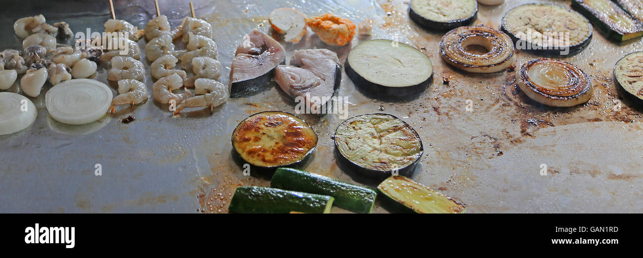 Pesce e verdure grigliate su piastre al ristorante durante il pranzo preparato Foto Stock