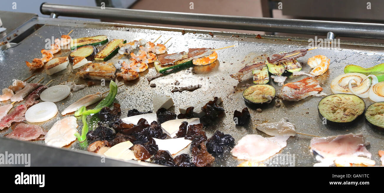 Pesce e verdure grigliate su piastre nel ristorante orientale durante il pranzo preparato Foto Stock