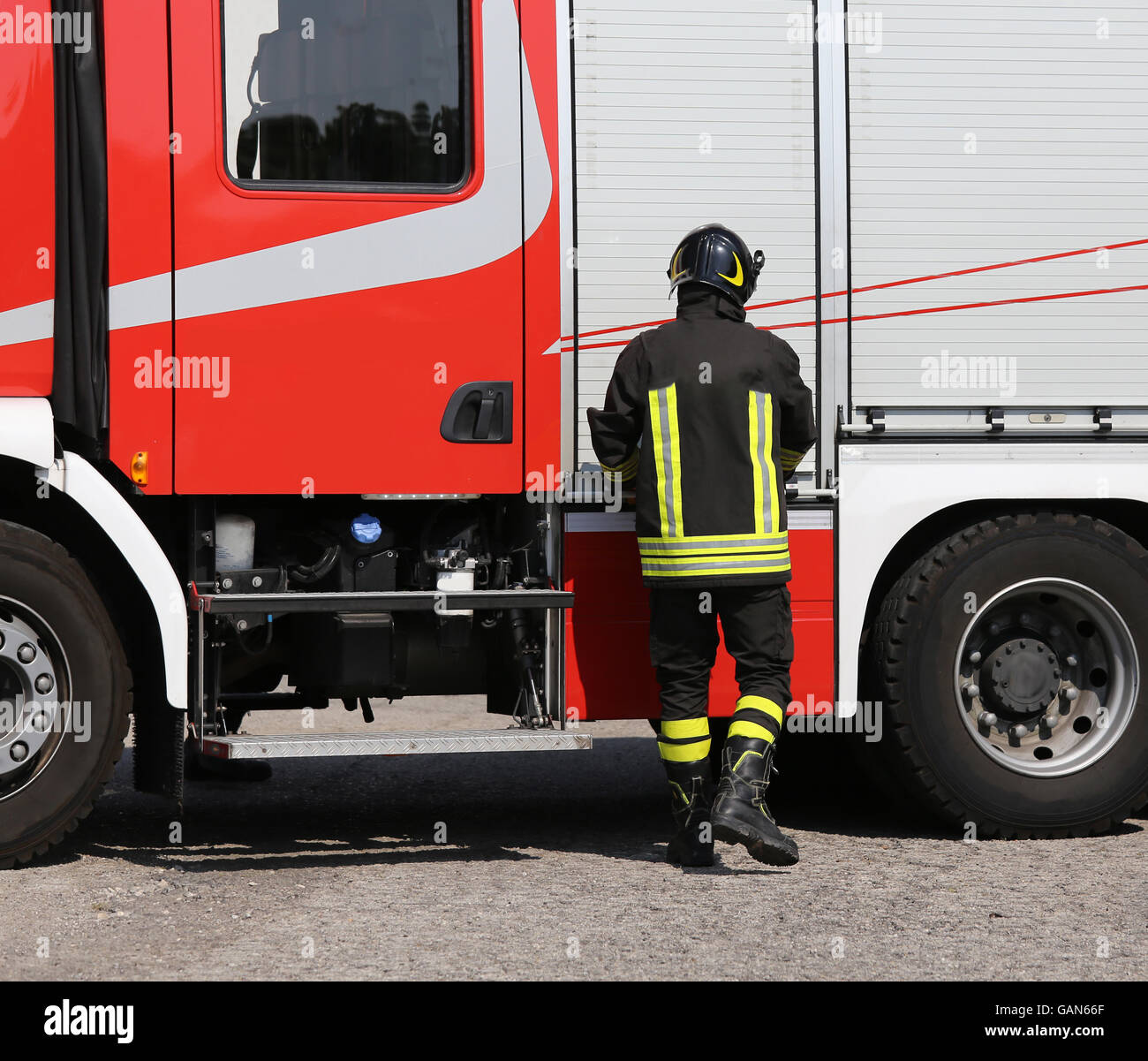 Coraggioso vigile del fuoco con il fuoco carrello motore durante un esercizio in caserma dei vigili del fuoco Foto Stock