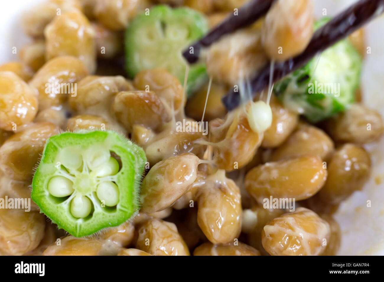 Primo piano di okra e soia fermentata conosciuta come Nato in Giappone con bastoncini. Cibo tradizionale giapponese a base di soia. Foto Stock