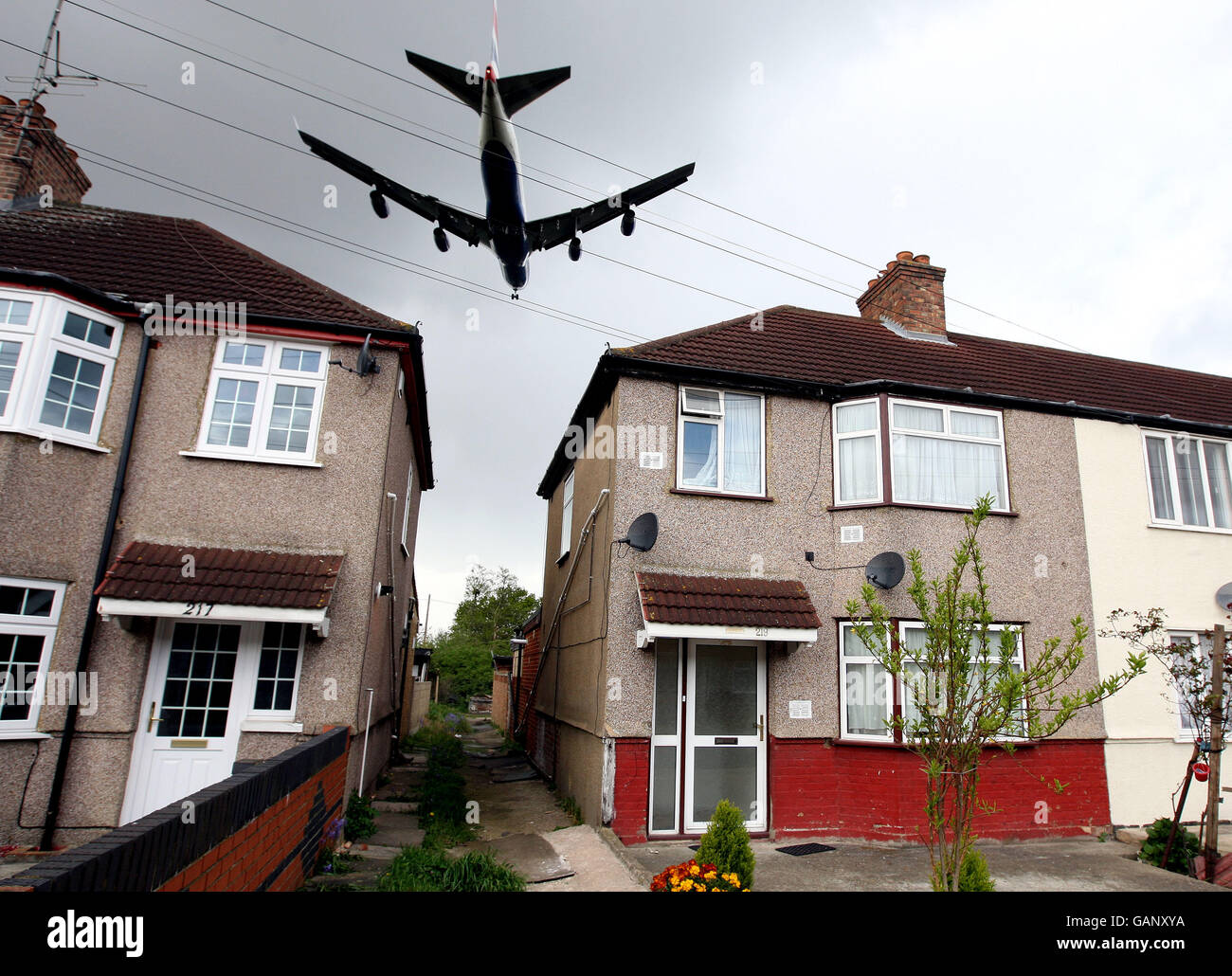 Una fotografia generica di un aereo che vola in basso su una proprietà immobiliare locale, sul suo approccio finale per atterrare sulla pista Nord all'aeroporto di Heathrow Foto Stock