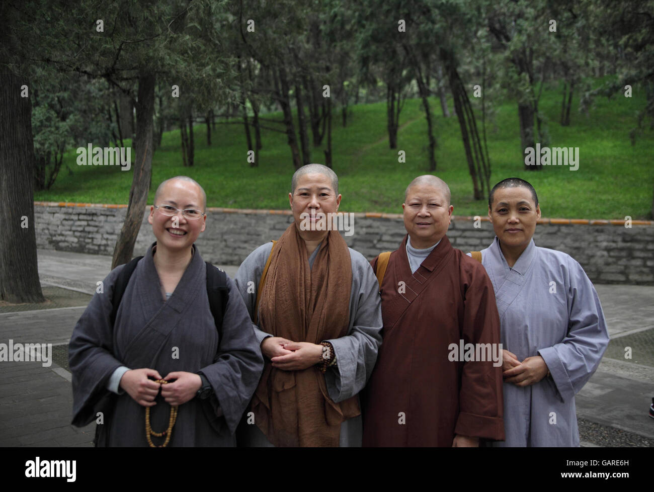 Quattro budhists, uomini e donne, i monaci e le monache, indossando abiti, le teste rasate, posa e sorriso per la fotocamera. Il palazzo d'Estate a Pechino, Cina. Foto Stock