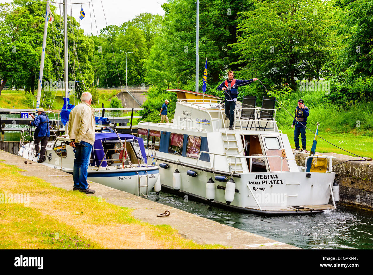 Motala, Svezia - 21 Giugno 2016: due barche di fianco a fianco in un blocco del canale. Barca equipaggi lavorano con funi e spettatore guardando a Foto Stock