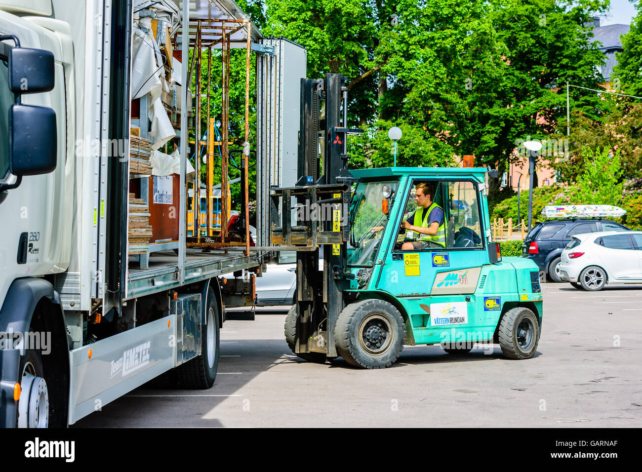 Motala, Svezia - 21 Giugno 2016: Lavoratore di carico o di scarico di una gabbia in acciaio dal retro di un carrello con un piccolo carrello elevatore. La vita reale sit Foto Stock