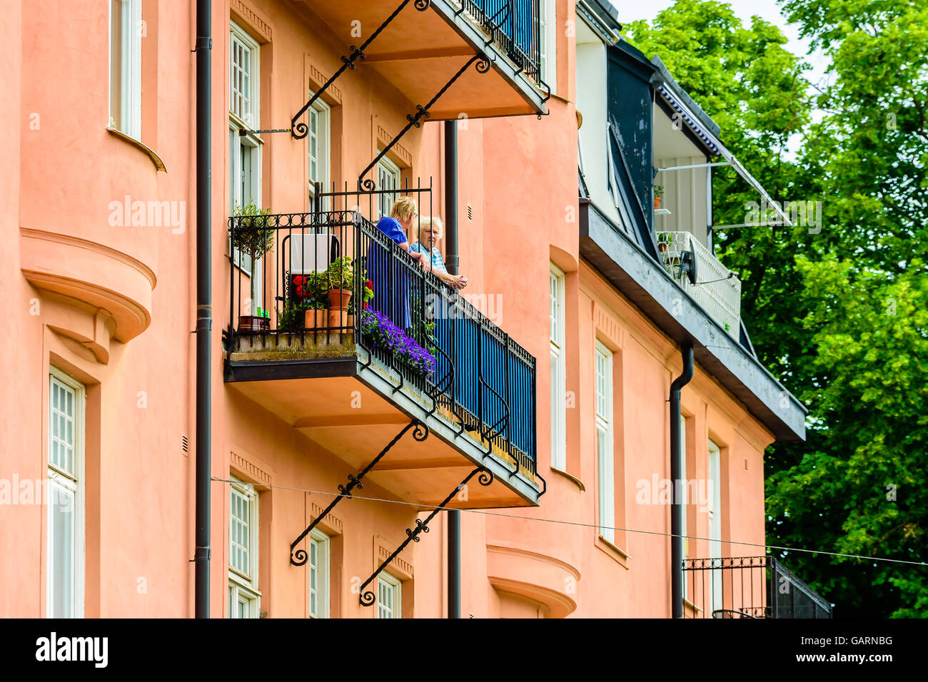 Motala, Svezia - 21 Giugno 2016: due senior donne parlare attraverso una recinzione su un balcone in un appartamento casa in città. Li reale Foto Stock