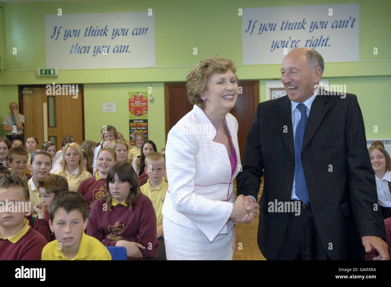 (Da sinistra a destra) il presidente irlandese Mary McAleese condivide una battuta con John Platt, il principale della Milburn Primary School, Coleraine, durante la sua visita alla scuola, mentre i dimostranti si riuniscono fuori dalle porte della Milburn Primary School, Coleraine per protestare contro la visita del presidente irlandese Mary McAleese alla scuola elementare dell'Irlanda del Nord. Foto Stock