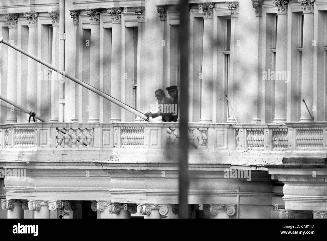 Uno degli ostaggi britannici nell'assediata ambasciata iraniana, Princes Gate, Londra, BBC suono recordist SIM Harris, 33 (a sinistra) apparve con un altro uomo, creduto essere PC Trevor Lock, vicino ad un palo di bandiera, sul balcone al primo piano. Sono apparse tre volte e hanno tenuto una lunga conversazione con due ufficiali di polizia sul marciapiede qui sotto. Foto Stock