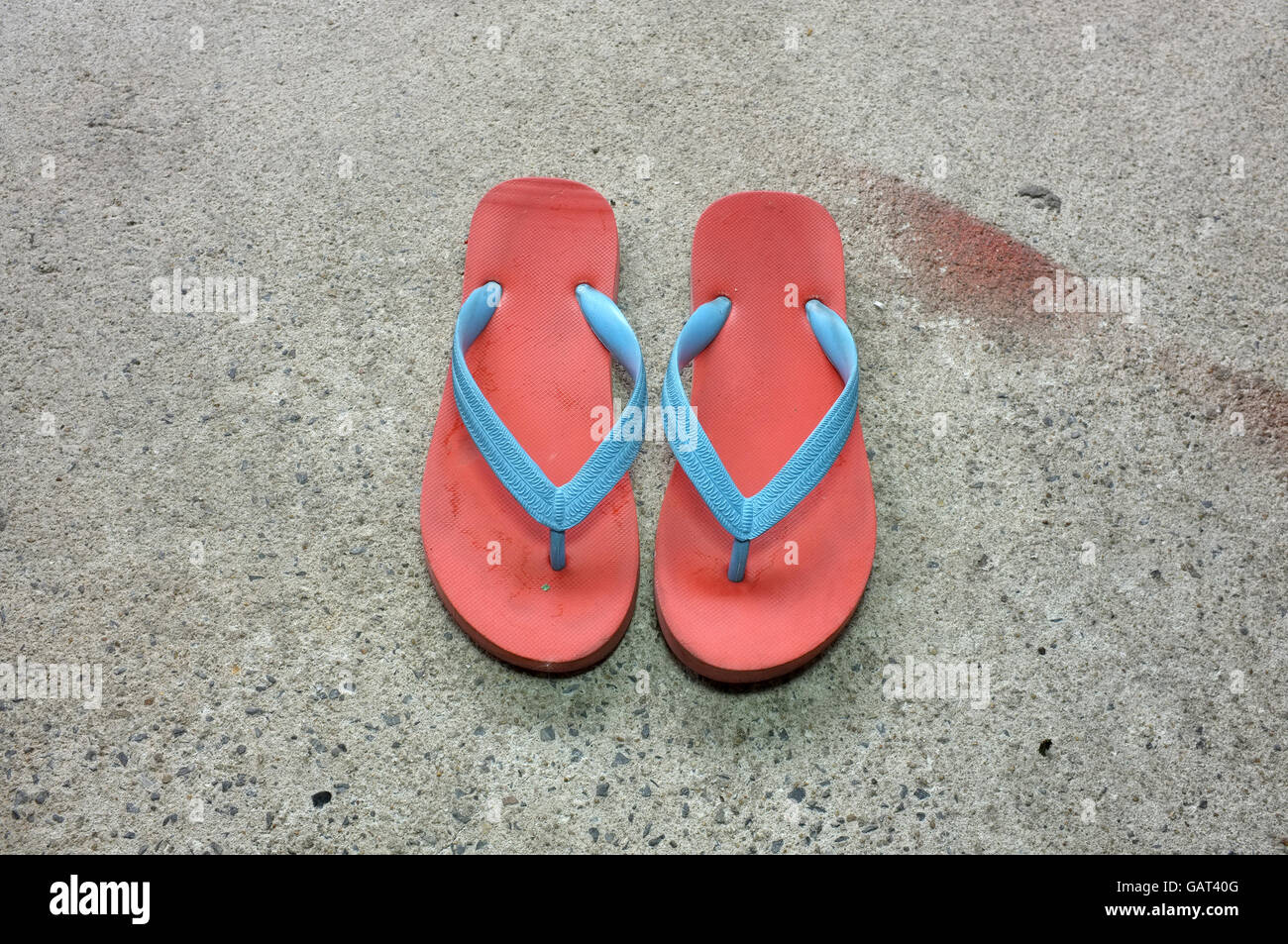 Coppia di red beach sandali di gomma con fascette blu sul pavimento di cemento Foto Stock