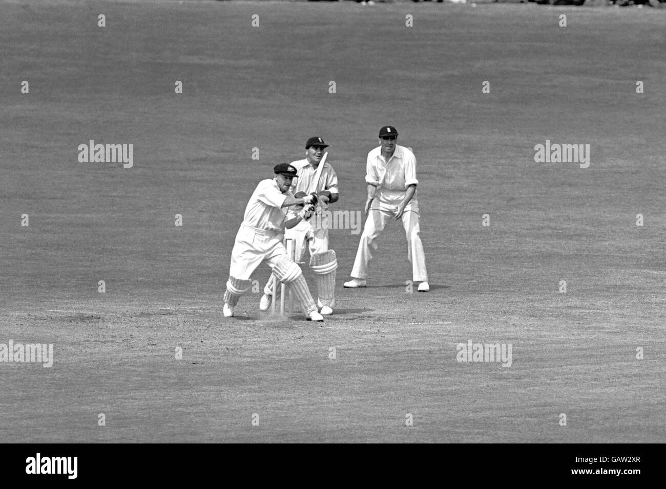 Il Don Bradman (l) dell'Australia tira la palla al confine per altre quattro corse durante le sue inning imbattute e vincitrici della partita del 173, guardate dal wicketkeeper inglese Godfrey Evans (c). L'Australia ha stabilito un nuovo record di test (che era fino al 1975) segnando 404 nel loro secondo inning per vincere la partita Foto Stock