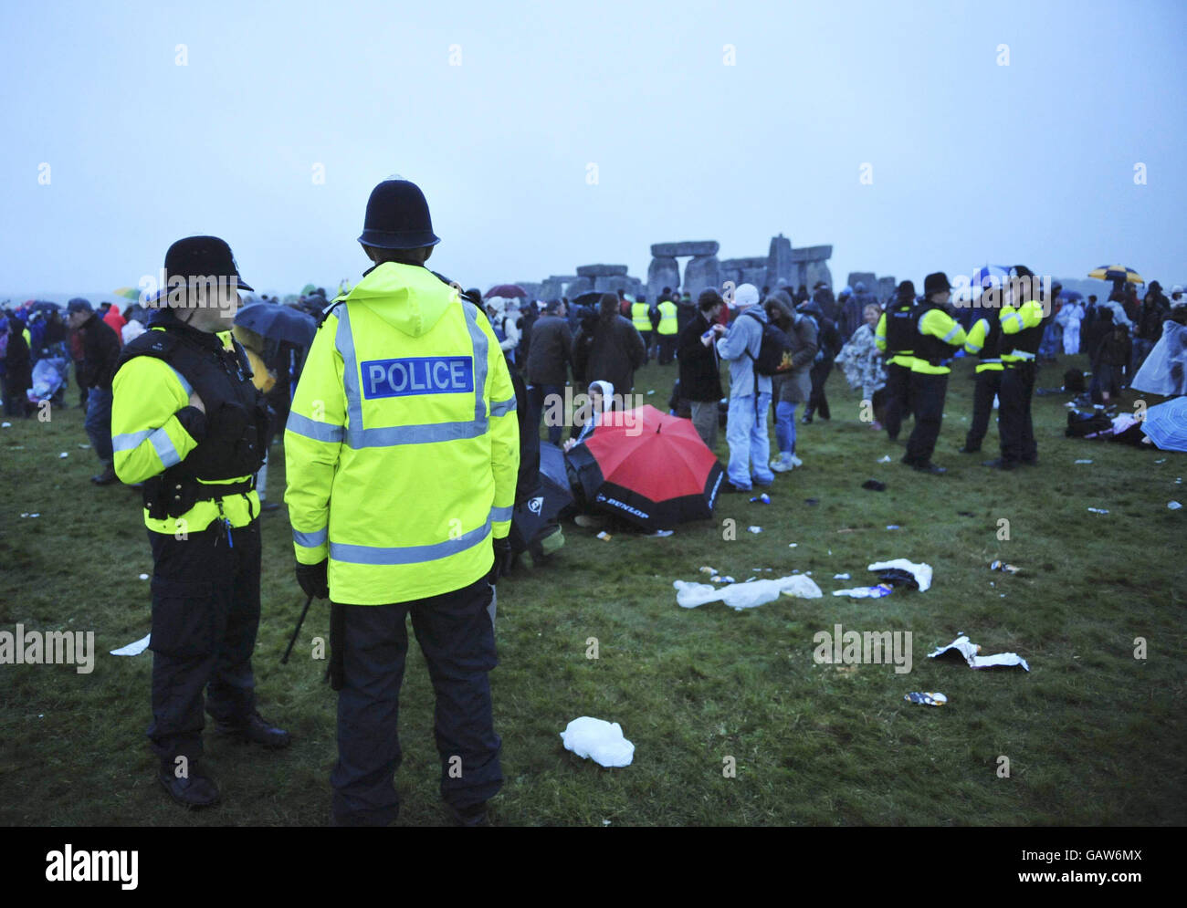 La polizia è presente sul sito come i rivelatori cantano nel frizzle di mattina presto come il maltempo e la pioggia impediscono il sole che splende la mattina del solstizio estivo a Stonehenge, Wiltshire. Foto Stock