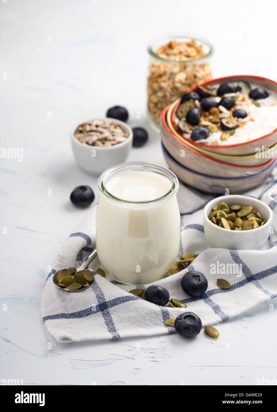 Alcuni yogurt naturale in un vasetto di vetro servita con una varietà di semi e granaglie Foto Stock