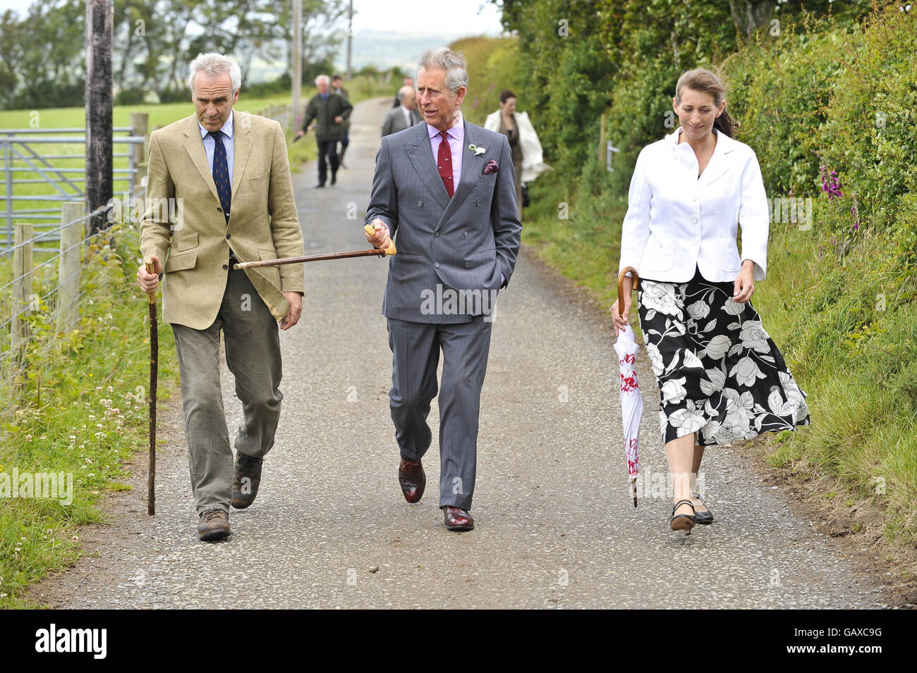 Il Principe del Galles (centro) cammina con i proprietari di Bwlchwernen Fawr Farm Patrick Holden (a sinistra) e sua moglie Becky Holden (a destra) lungo la corsia verso la fattoria di Llangybi, Lampeter, Galles. Foto Stock