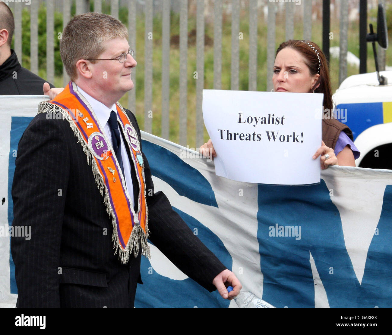 Un Orangeman cammina accanto a un protester nazionalista sulla Spirngfield Road, a ovest di Belfast, Irlanda del Nord. Foto Stock