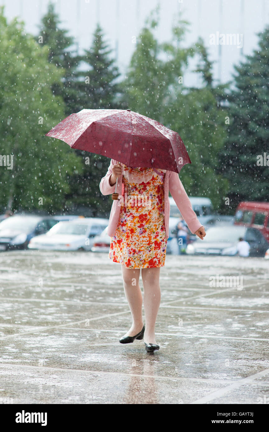 Ragazza con un ombrello sotto la pioggia corre attraverso le pozzanghere  Foto stock - Alamy